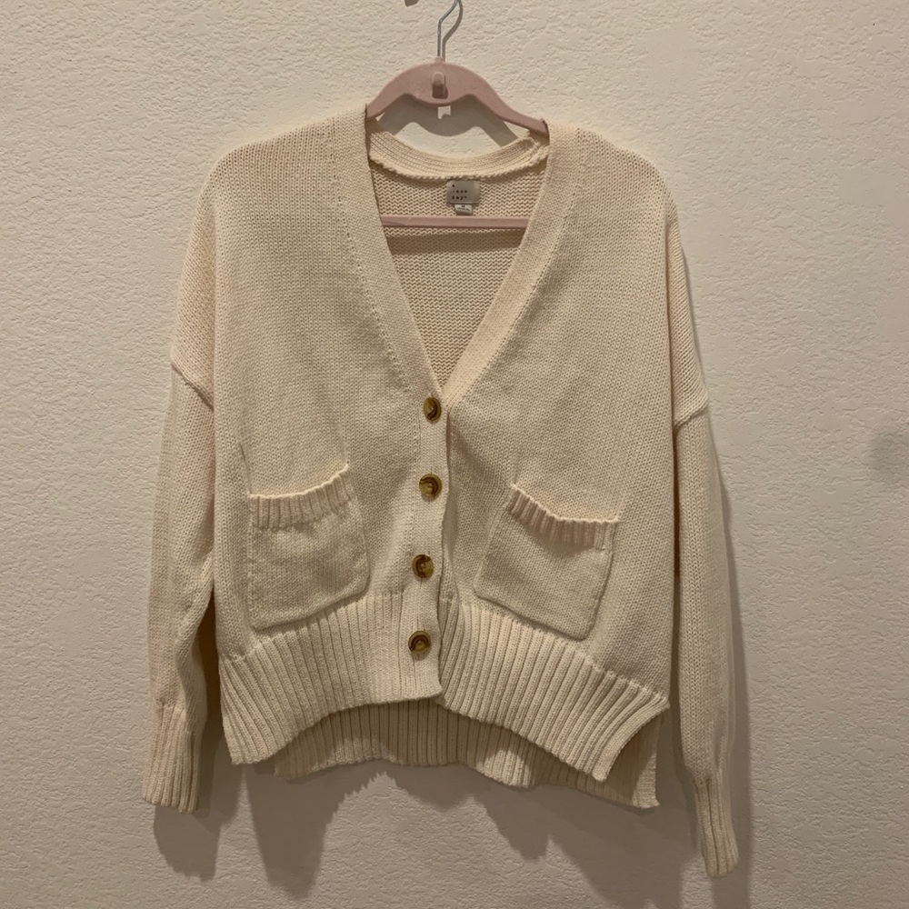Cream flowy, casual cardigan with brown buttons.